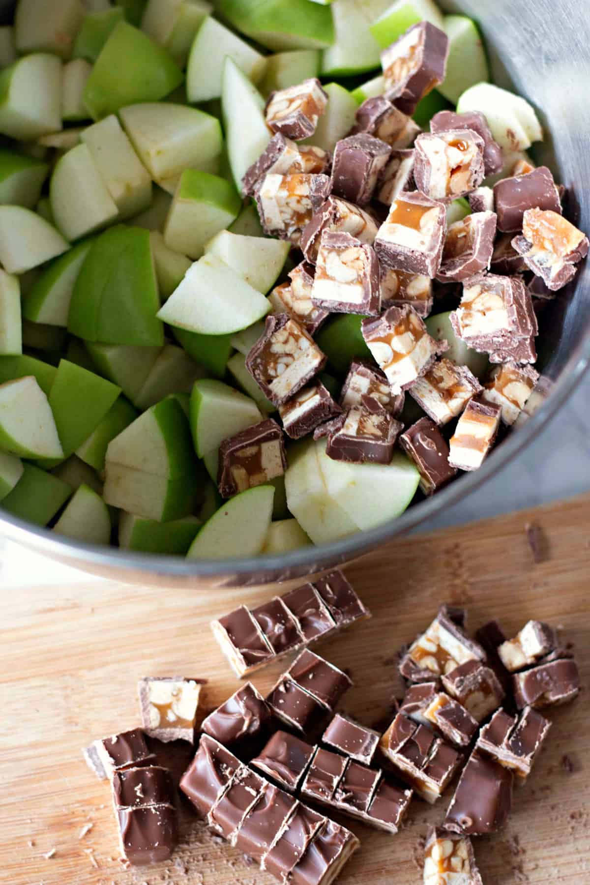 Close-up of chopped green apples and Snickers bars in a bowl, ready to be mixed with the cream cheese mixture.