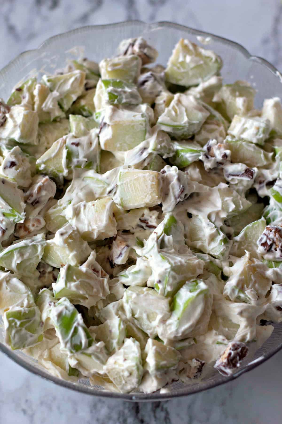 A bowl of Snickers Salad being mixed, showing the whipped cream and cream cheese folded into the apples and Snickers pieces.