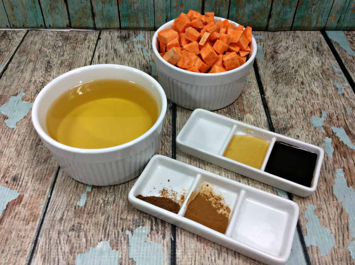 Ingredients for Sweet Potato Butter including diced sweet potatoes, spices, and sweeteners arranged on a rustic wooden table.