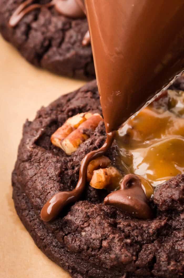 Chocolate being drizzled over the caramel on cookies