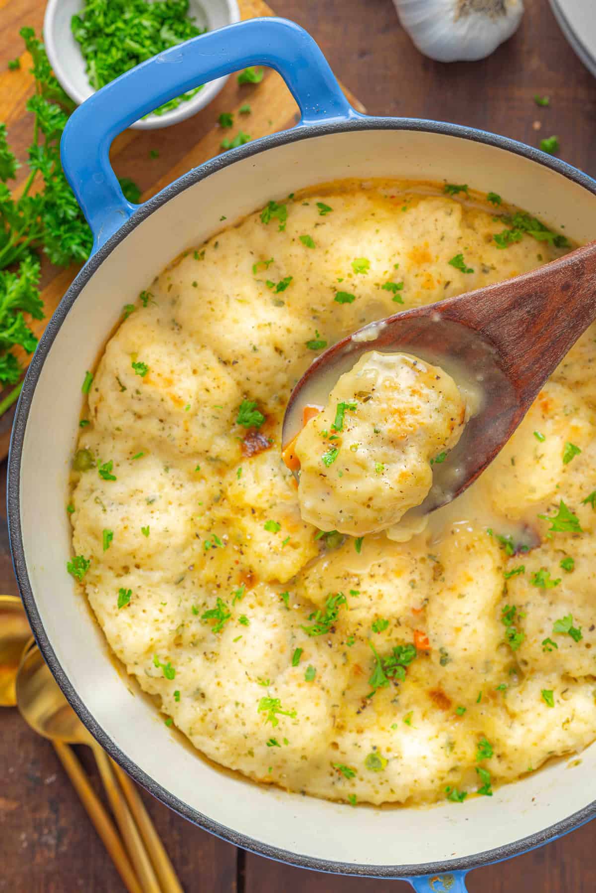 There's no better comfort food than this Bisquick Chicken and Dumplings recipe. It's hearty, filling, and easy to make. A wooden spoon holding a Bisquick dumpling over soup