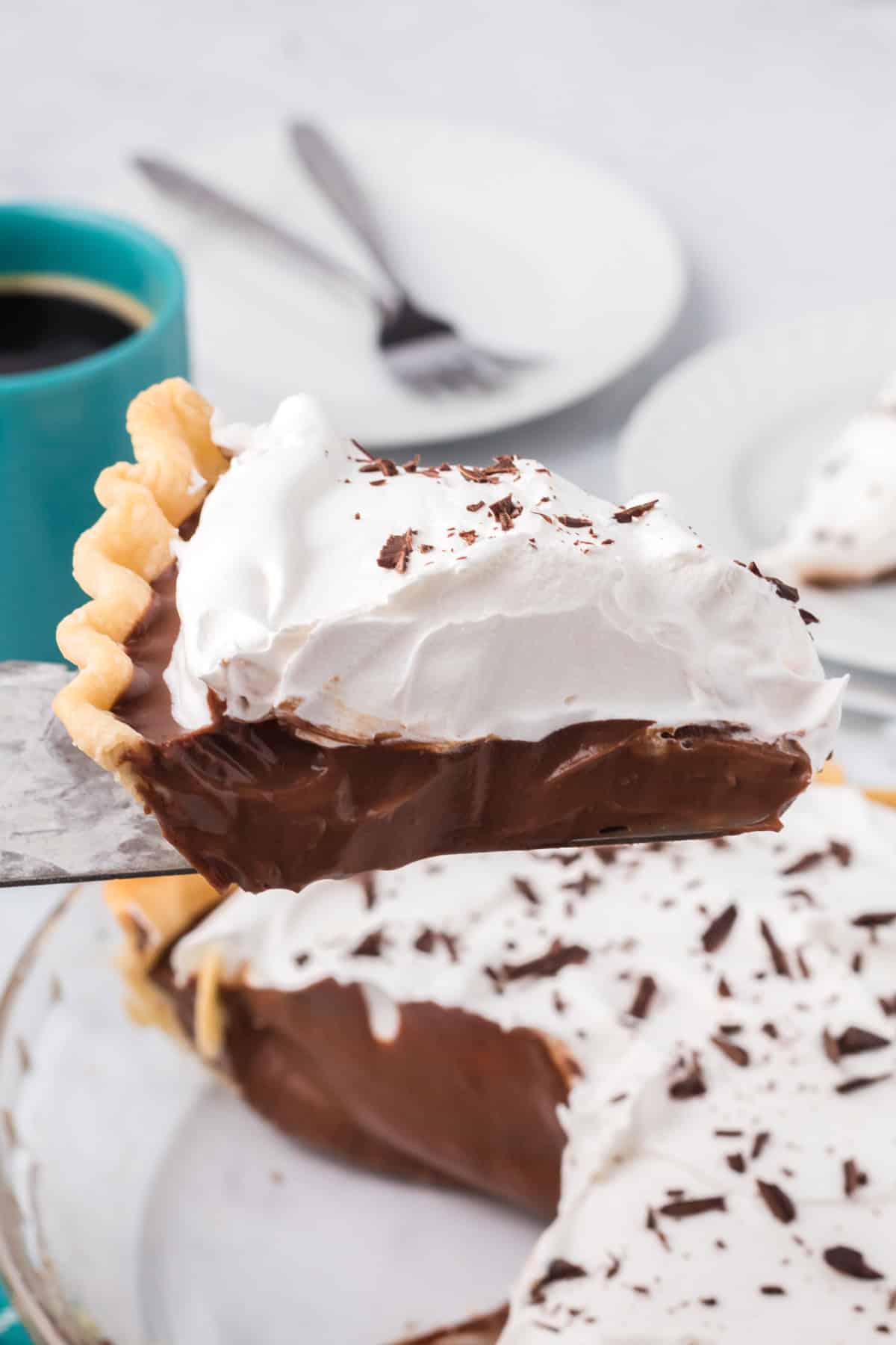 Indulge in the ultimate chocolate lover’s dream with this irresistible Chocolate Cream Pie! With a smooth, creamy filling and a buttery, flaky crust, this dessert strikes the perfect balance between rich decadence and delightful simplicity. Topped with a cloud of fresh whipped cream and delicate chocolate shavings, every bite is a luxurious experience. A close-up shot of a slice of chocolate cream pie on a plate with a fork, showcasing the thick layer of whipped cream and chocolate filling.