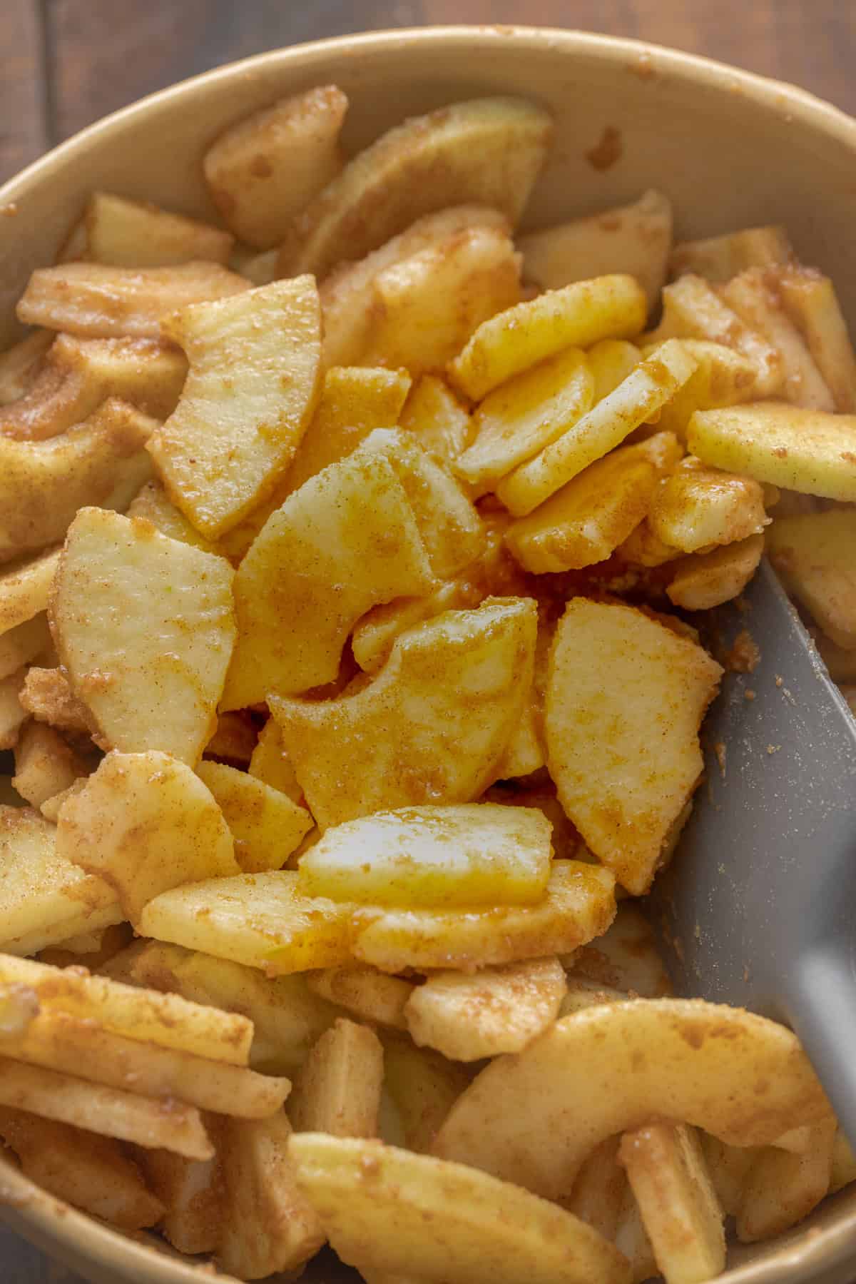 Close-up of freshly sliced apple pieces mixed with cinnamon and sugar, sitting in a bowl, ready to be used as the pie filling.