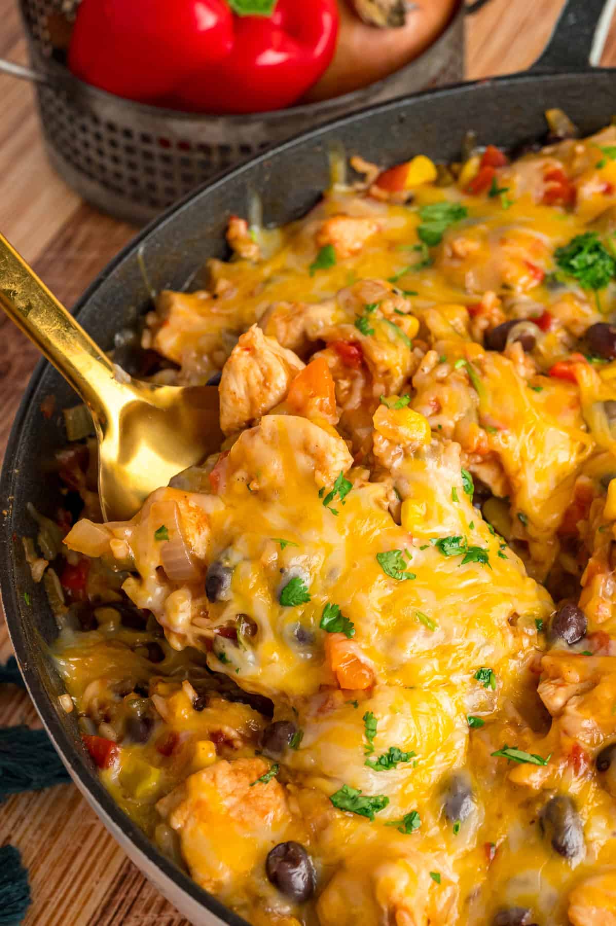 Fiesta Chicken is an easy one skillet dinner featuring juicy chicken breasts and Tex-Mex ingredients like rice, black beans, corn, & chilies. A spoon diving into a skillet of fiesta chicken