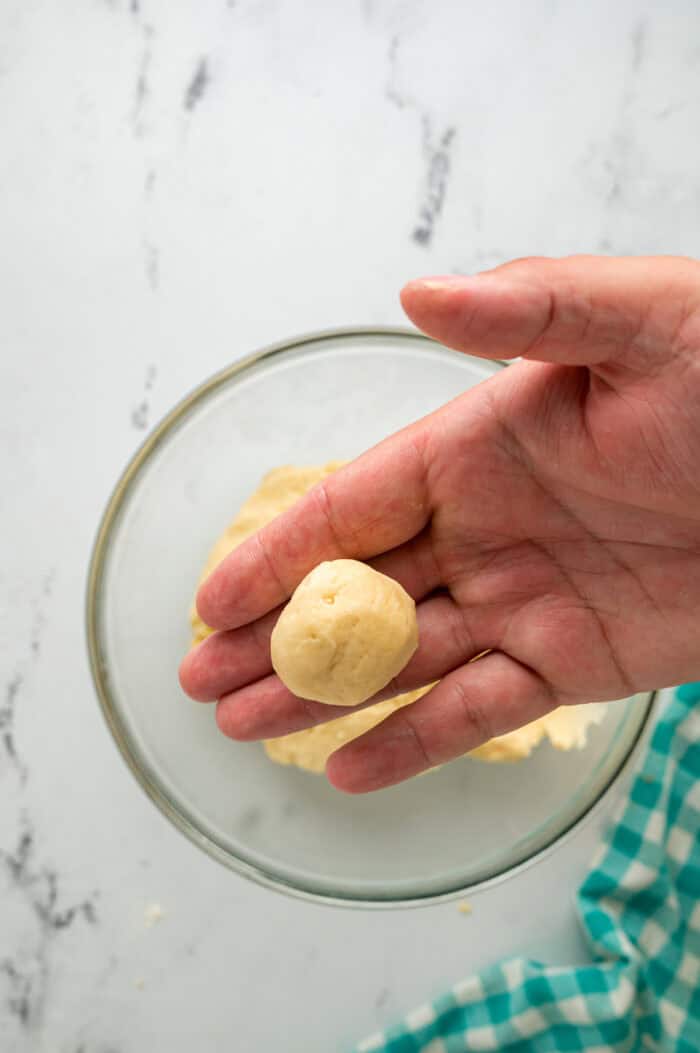 A hand holding a ball of cookie dough