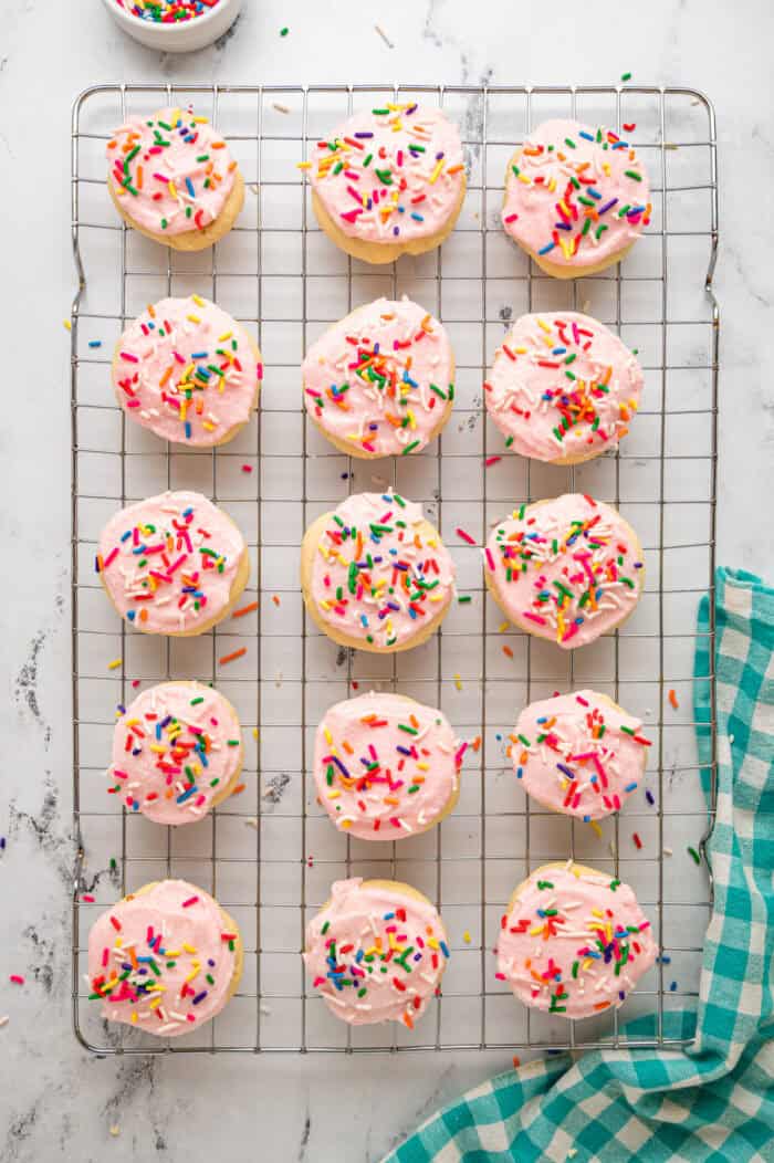 Lofthouse sugar cookies with pink frosting and sprinkles on a cooling rack
