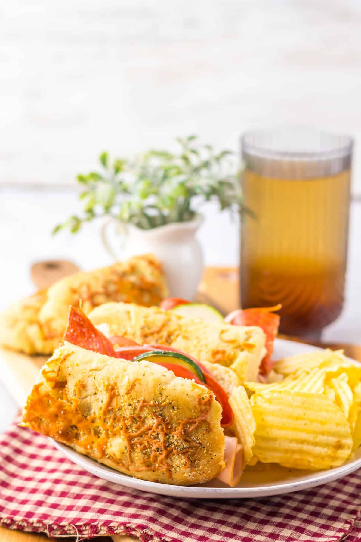 Italian Herb Cheese Bread made into sub sandwich on white plate with potato chips