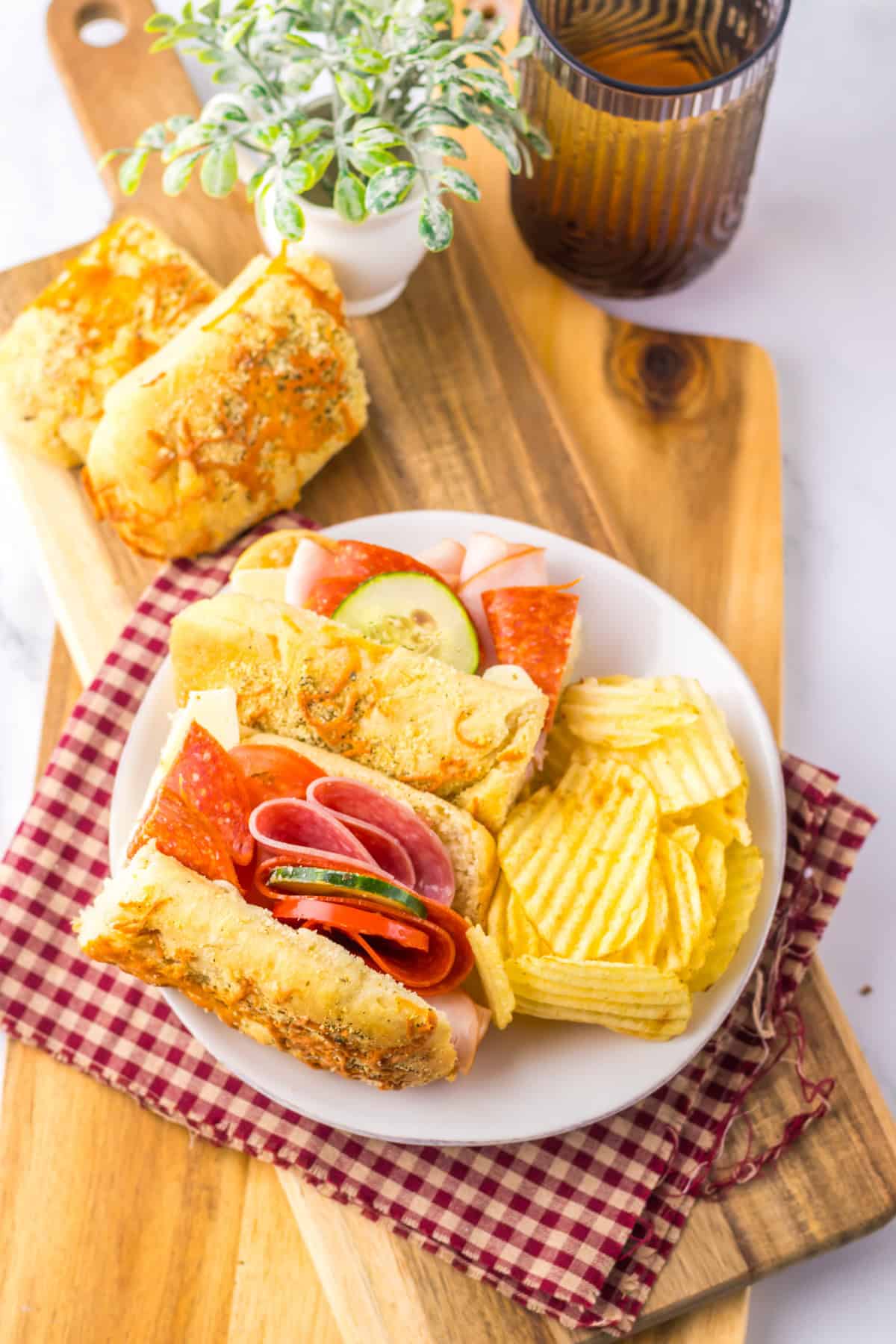 Italian Herb Cheese Bread sub sandwich with potato chips on white plate
