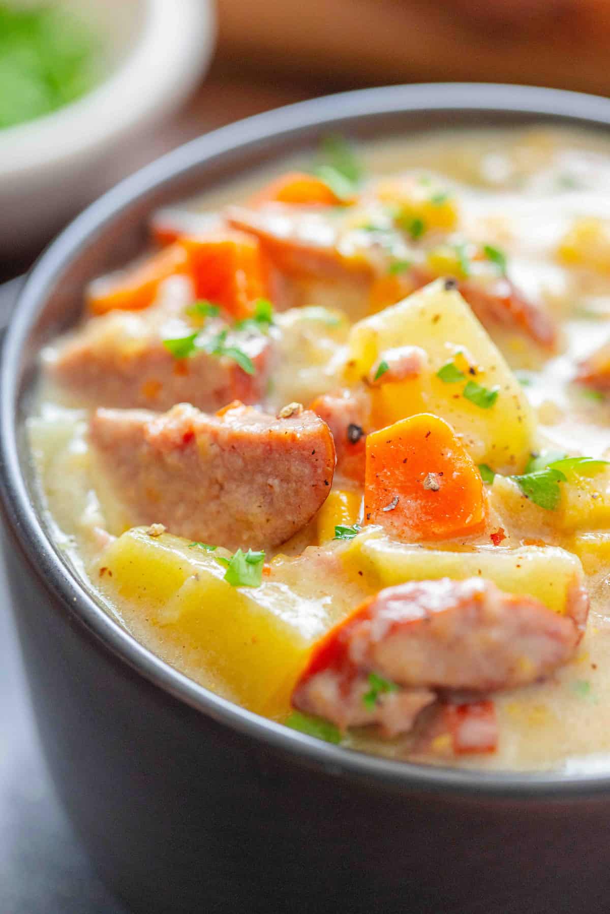 Made with chunks of kielbasa, potatoes, and veggies in a creamy, cheesy broth, this Kielbasa Potato Soup is hearty, filling, and so easy! Close up of a bowl of kielbasa potato soup