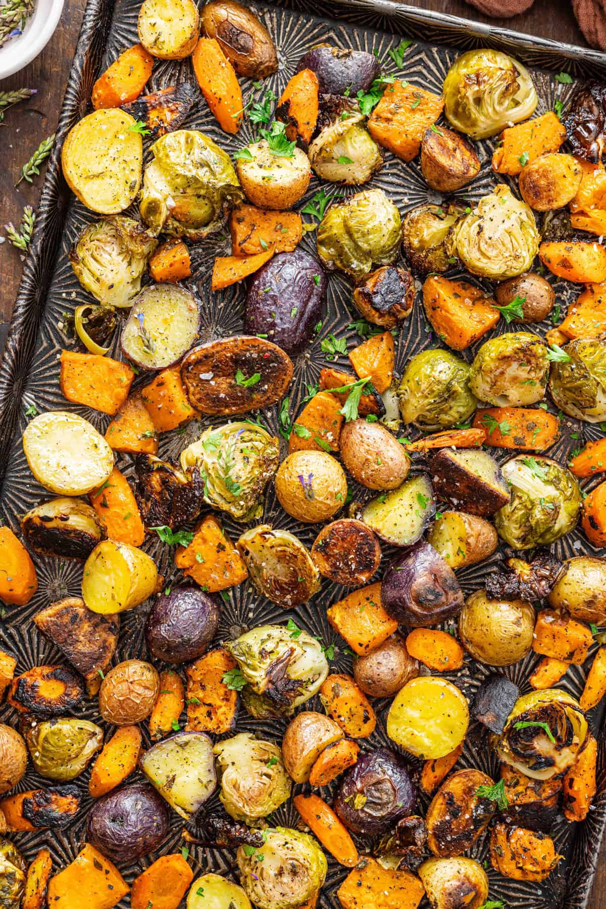Brussels sprouts, carrots, and potatoes are tossed with oil and herbs then roasted to perfection in this Oven Roasted Vegetables recipe. Overhead view of oven roasted vegetables on a baking sheet