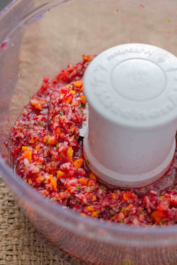 Chunks of cranberries, orange, and jalapeno in a food processor