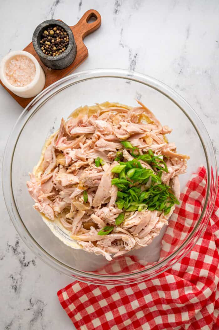 Shredded chicken and green onions added to a bowl with condensed soup