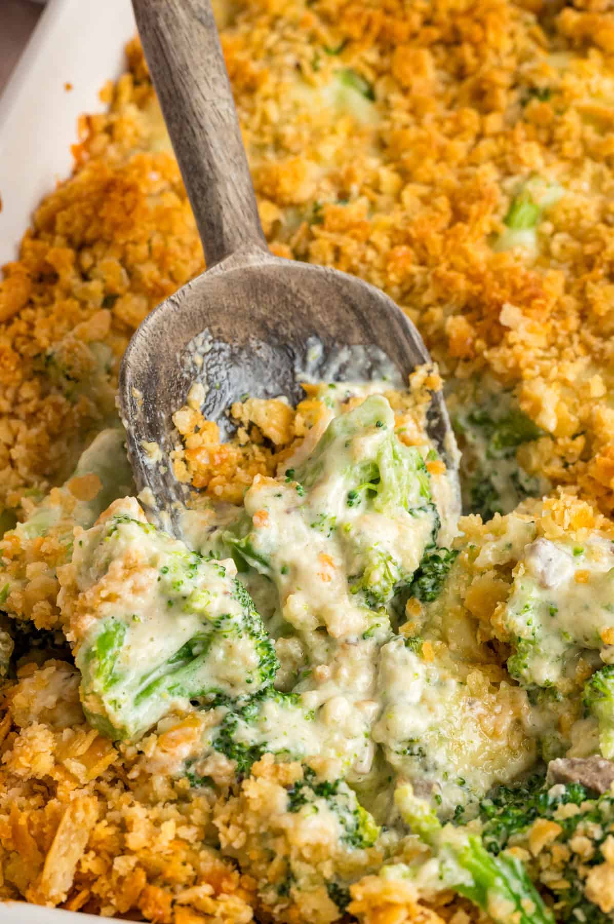 A spoon in a dish of broccoli and cheese casserole