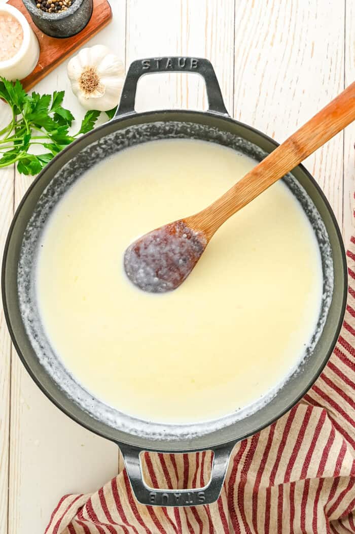 A spatula stirring alfredo sauce