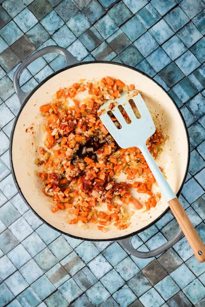 Tomato paste added to diced carrots and onions