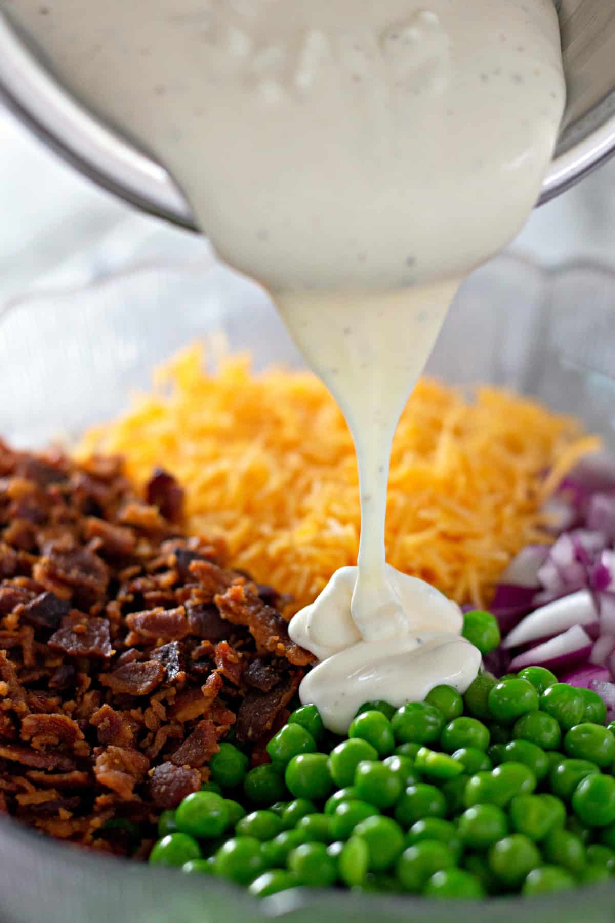 dressing poured over ingredients for pea salad