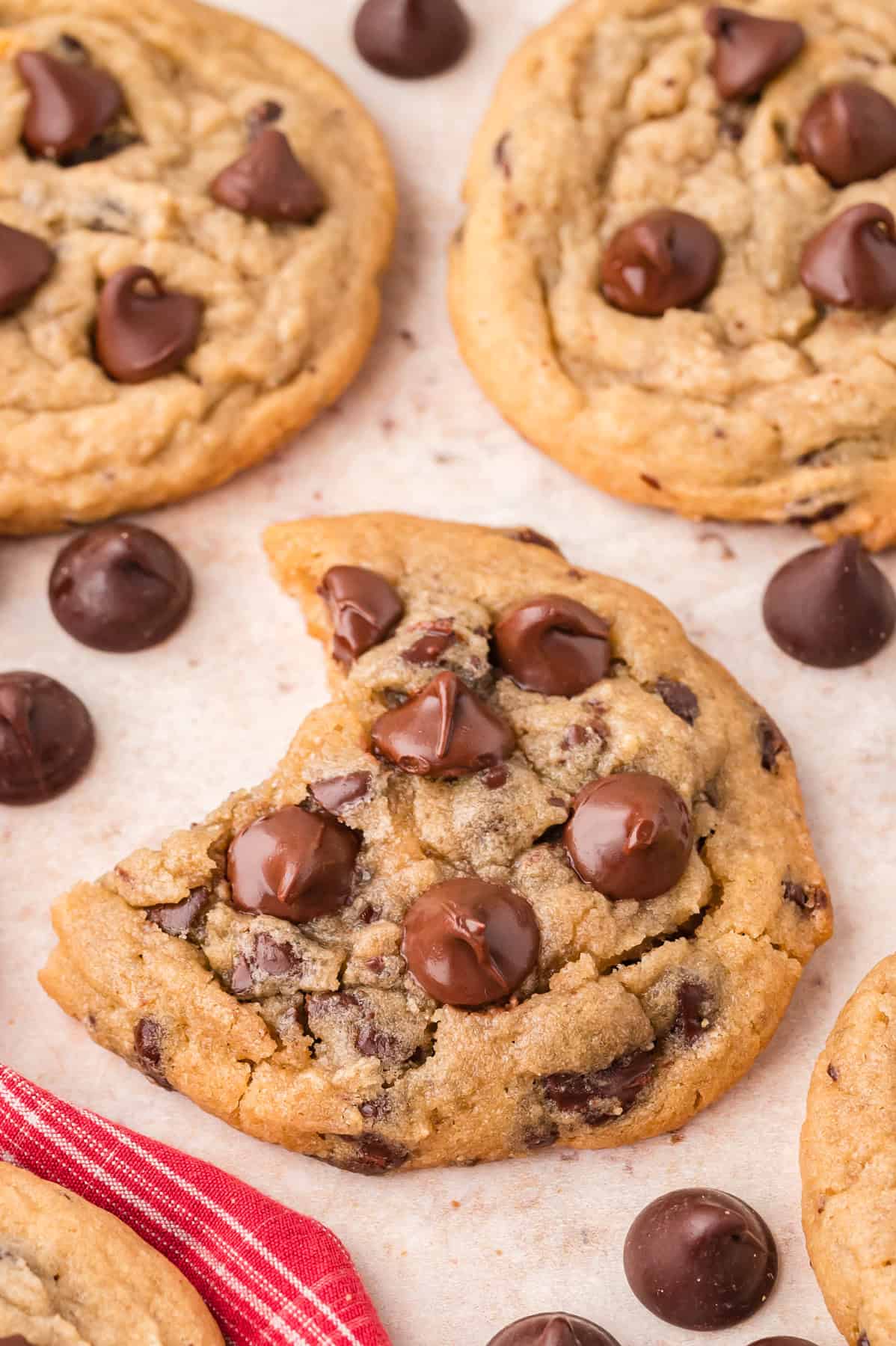 Toll house cookies on a baking sheet, one with a bite missing