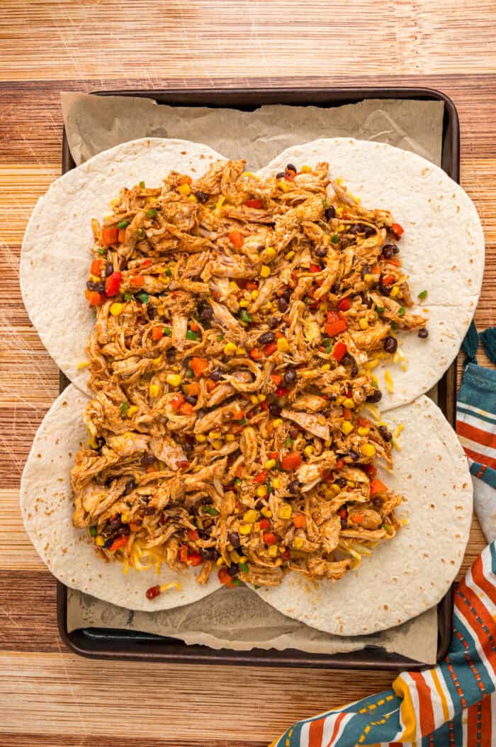 Quesadilla filling spread on a sheet pan of tortillas