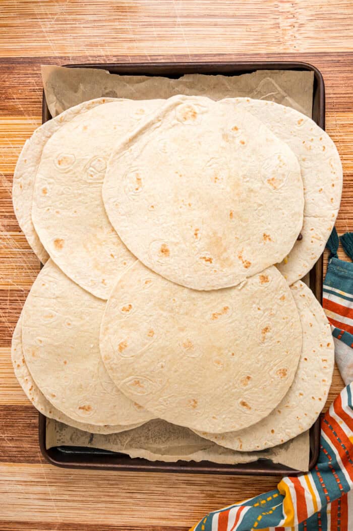 Tortillas on top of quesadilla filling on a baking sheet