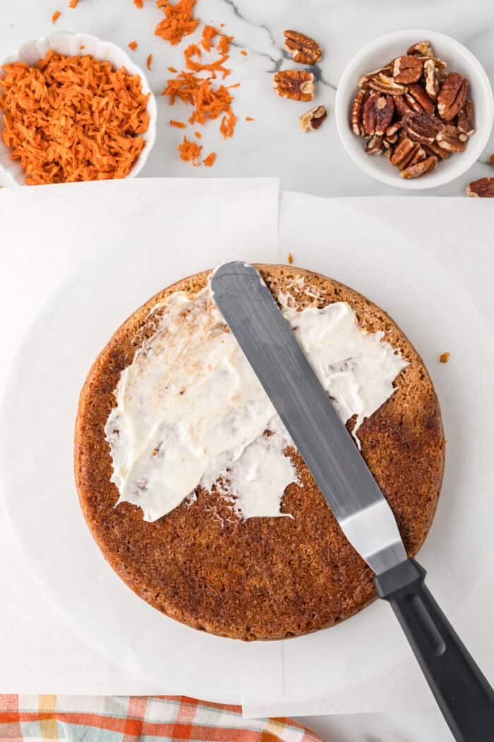 Spreading cream cheese frosting on a round carrot cake