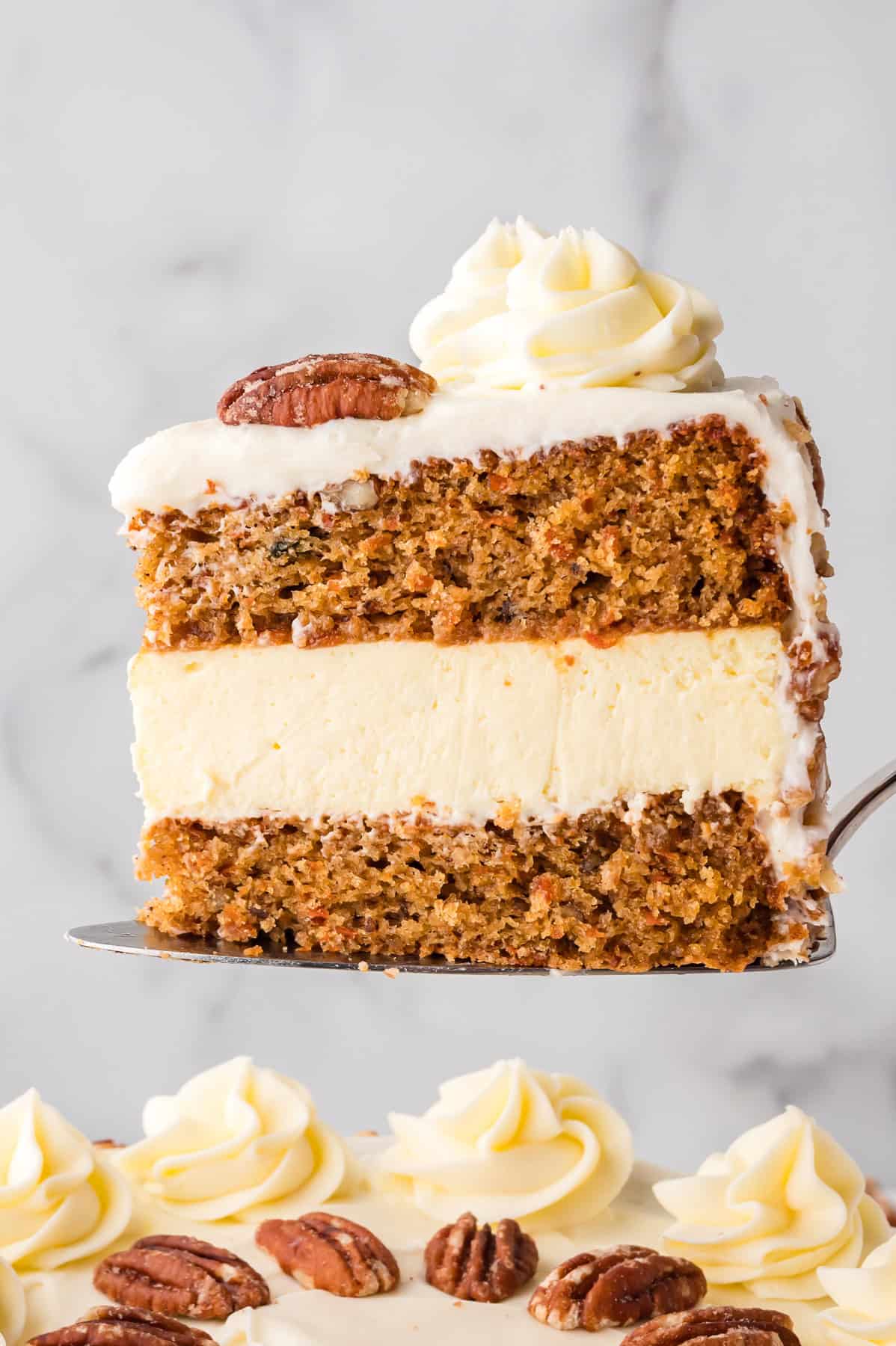 A slice of carrot cake cheesecake on a serving spatula