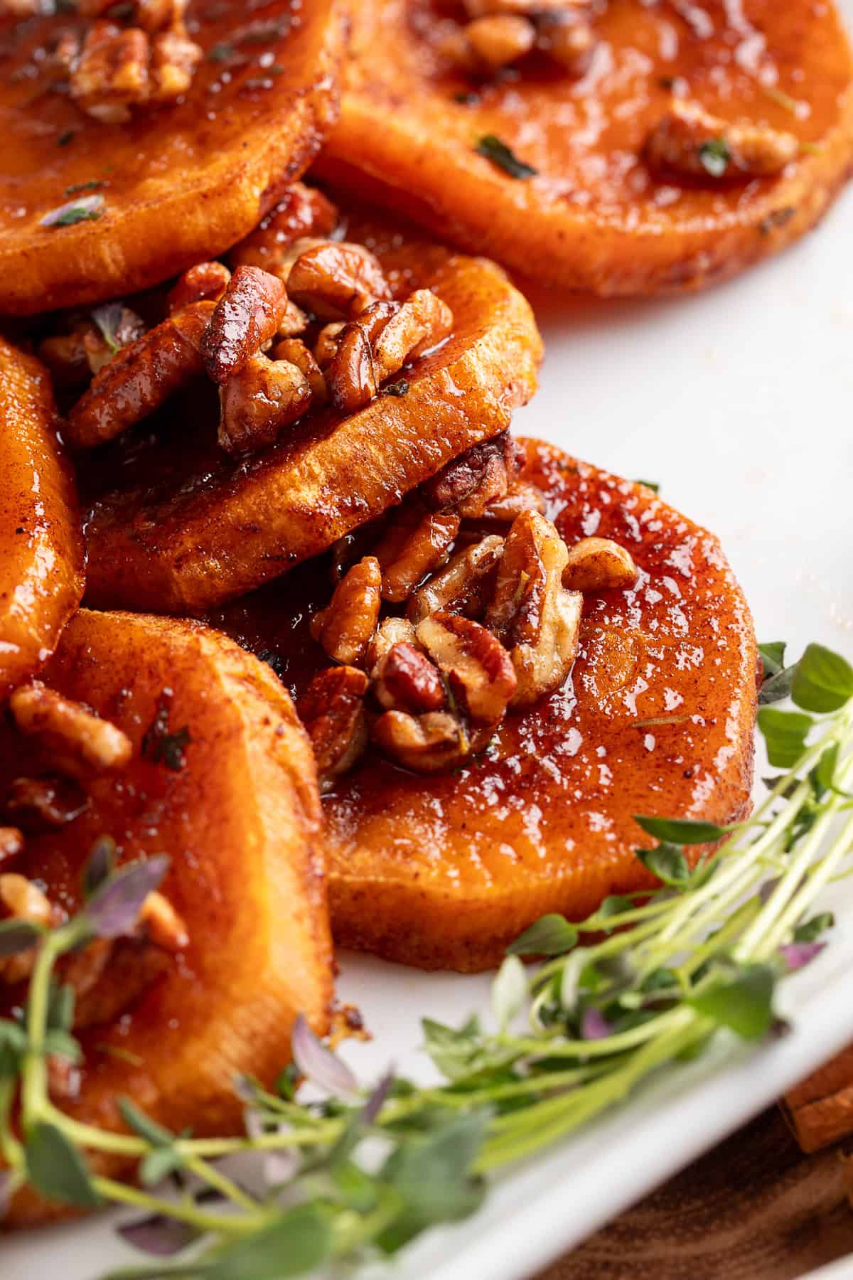 These simple Roasted Sweet Potatoes are a flavorful and versatile side dish that pairs perfectly with any meal. They’re caramelized on the outside, tender on the inside, and naturally sweet and buttery—my favorite way to enjoy sweet potatoes! A plated serving of roasted sweet potatoes with pecans on a white dish.