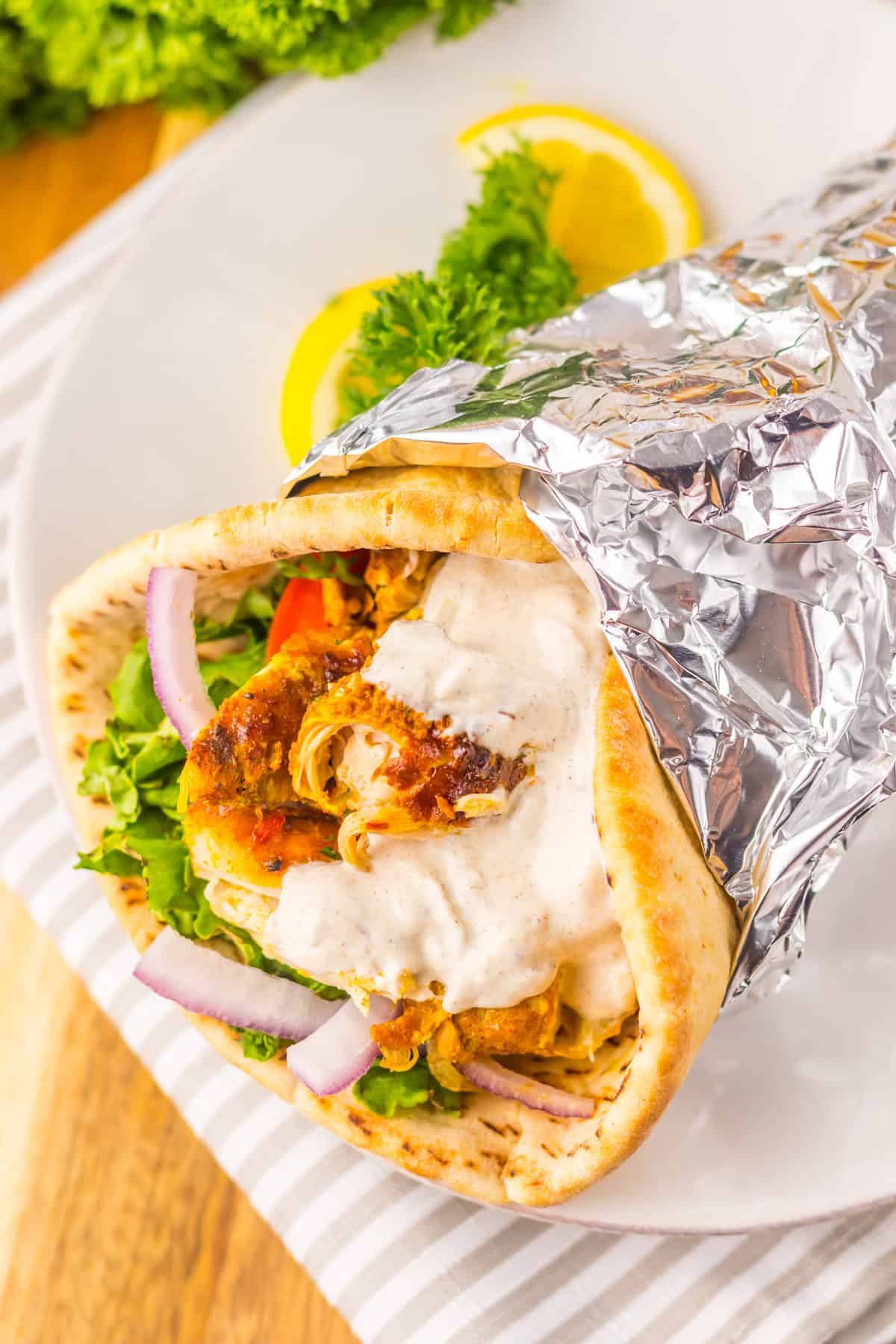 Marinated chicken thighs slow cook until tender in this Chicken Shawarma recipe. Serve piled high on pita with veggies & yogurt sauce. Chicken shawarma in a pita