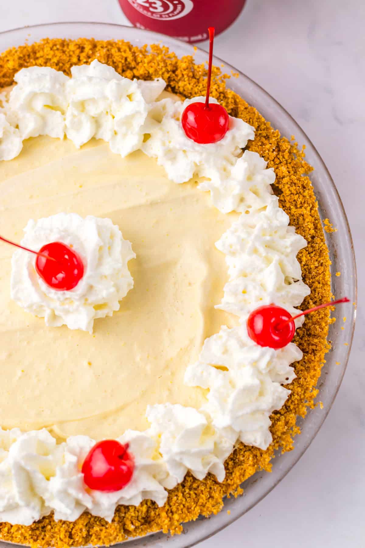 Top view of Dr Pepper pie in a graham cracker crust, decorated with whipped cream and cherries around the edge.