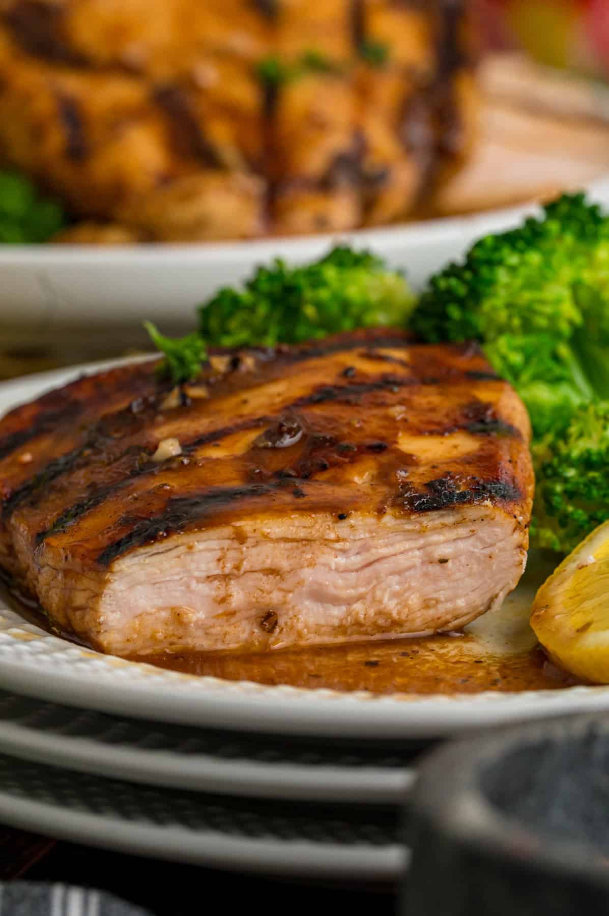 Grilled chicken with a piece sliced off on a plate with broccoli