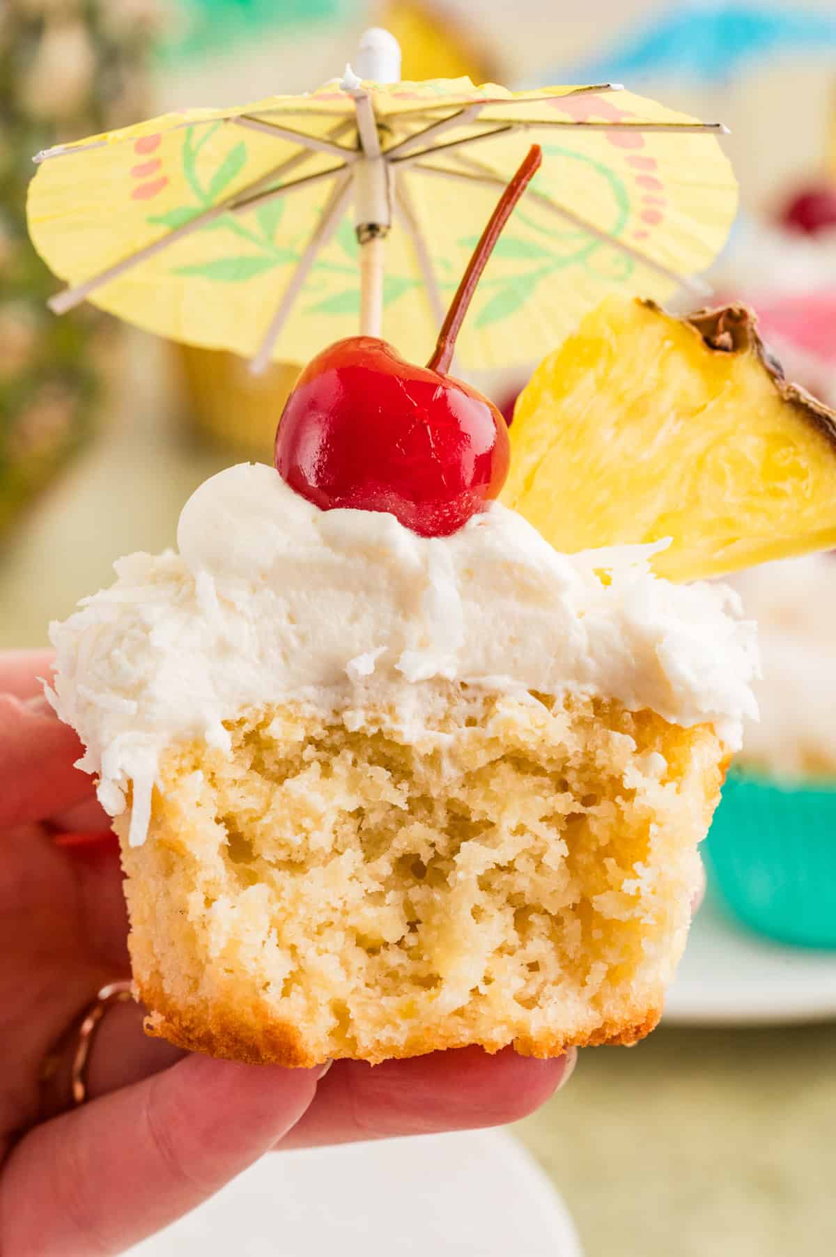 A hand holding a pina colada cupcake showing the inside