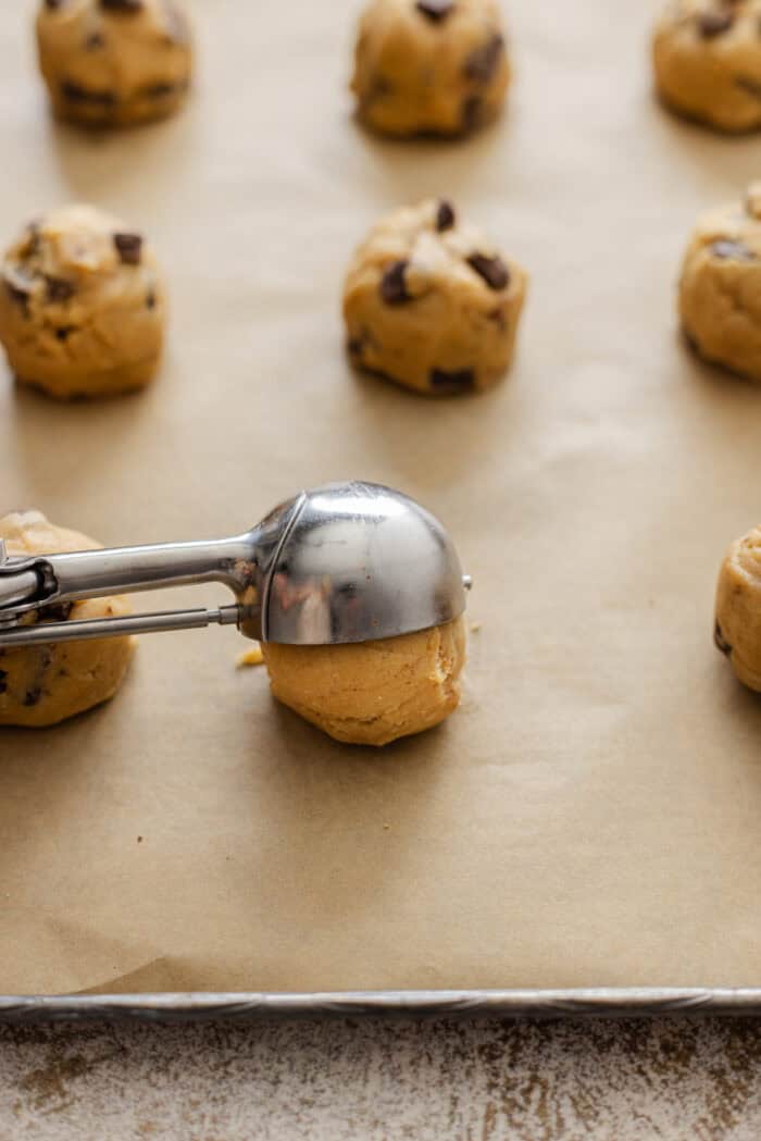 Using a cookie scoop to drop balls of cookie dough on a baking sheet