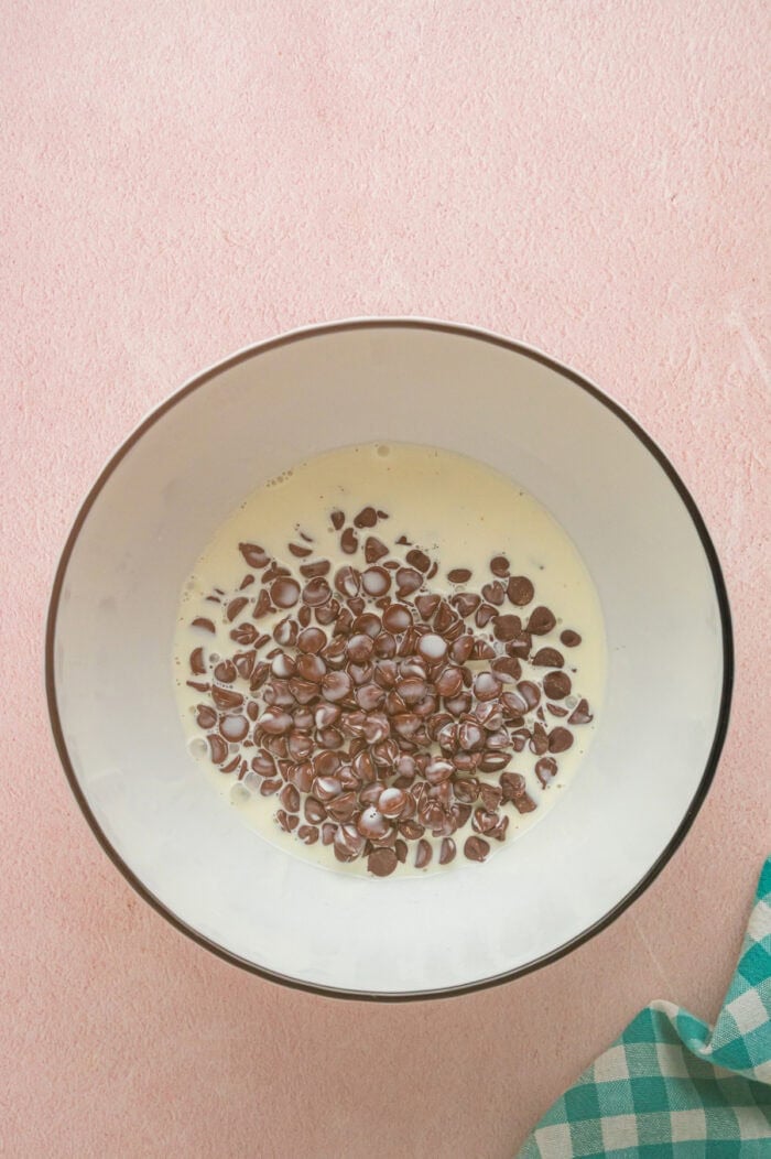 With dense, chewy brownies topped with frosting and rainbow candy-coated chocolate chips, these Cosmic Brownies are a nostalgic treat. Chocolate chips and heavy cream in a bowl