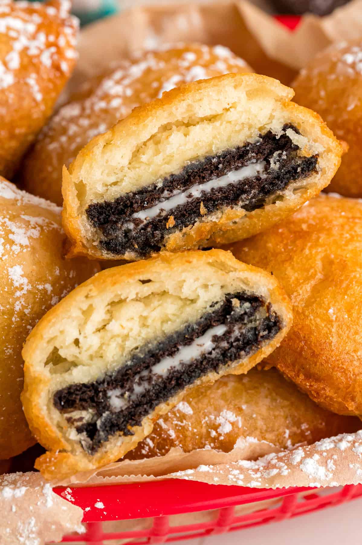 With Oreos coated in pancake batter and fried to golden perfection, this Deep Fried Oreos recipe turns fair food into an anytime treat. Close up of a basket of deep fried Oreos, with one cut in half to show the inside