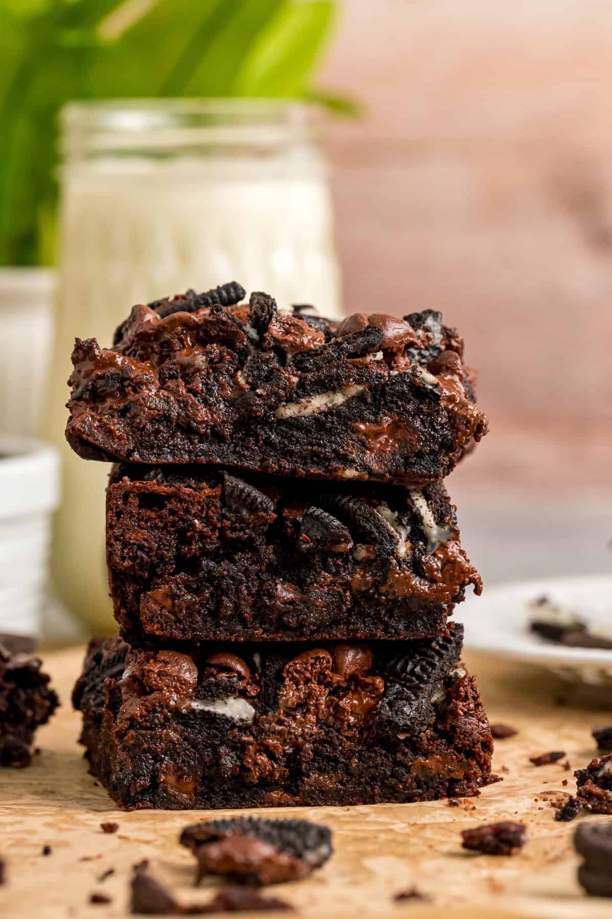 A stack of three Oreo brownies in front of a glass of milk