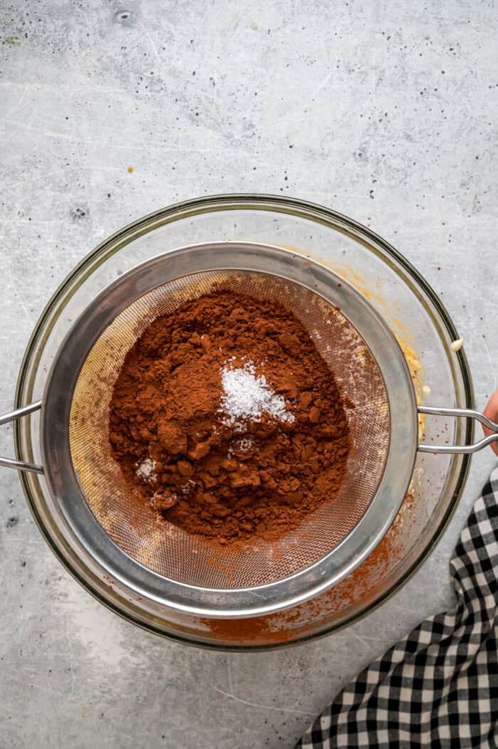 Sifting cocoa powder into brownie batter