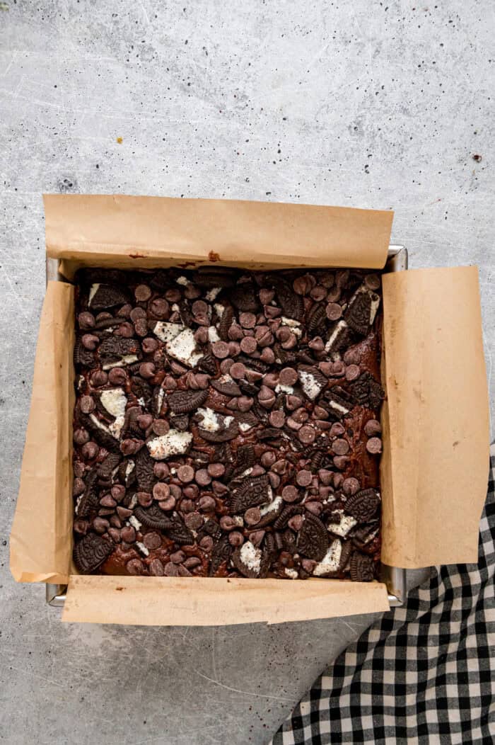 Oreo pieces and chocolate chips on top of brownie batter
