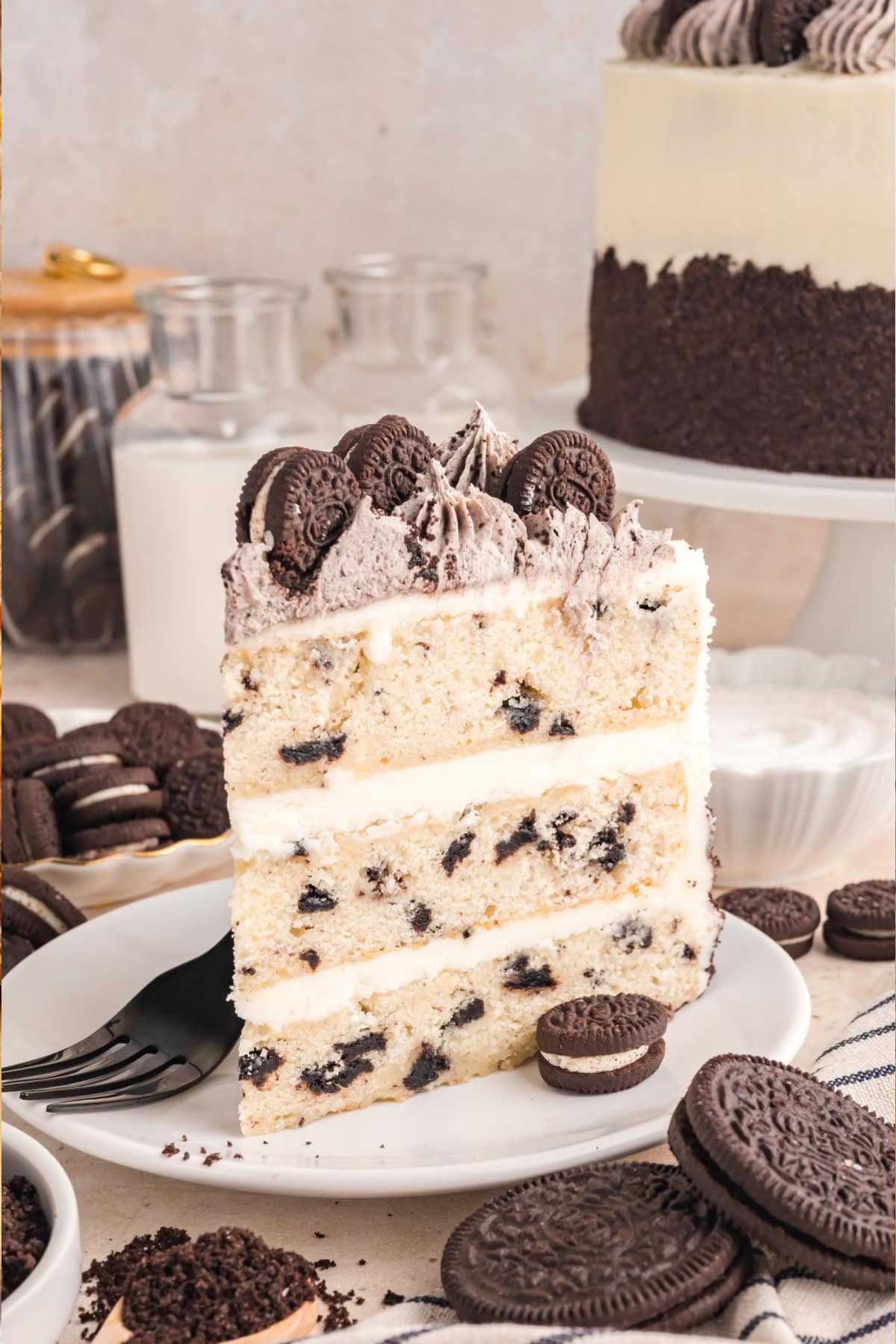 This Oreo Cake features a soft vanilla cake mixed with crushed Oreos, layered with creamy vanilla buttercream, and decorated with Oreos. Oreo Cake Slice