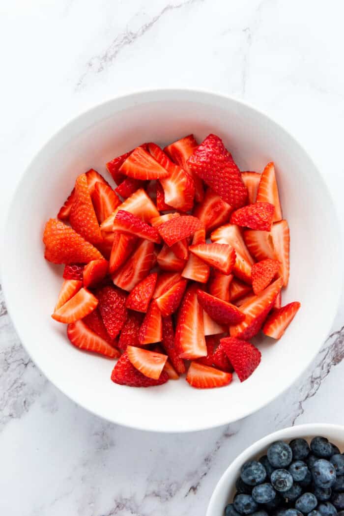 This 4th of July Fruit Salad is so festive and easy to make! It's perfect for Memorial Day, 4th of July or any patriotic gathering. cut strawberries in a bowl