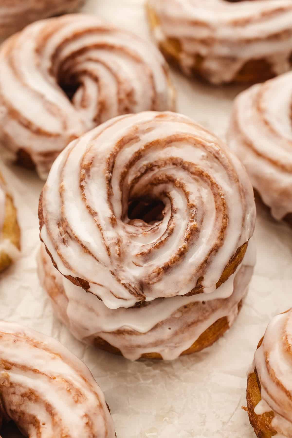 These French Cruller Donuts are crisp on the outside, impossibly light and airy on the inside, and finished with a sweet, glossy glaze. Overhead view of a stack of glazed French crullers