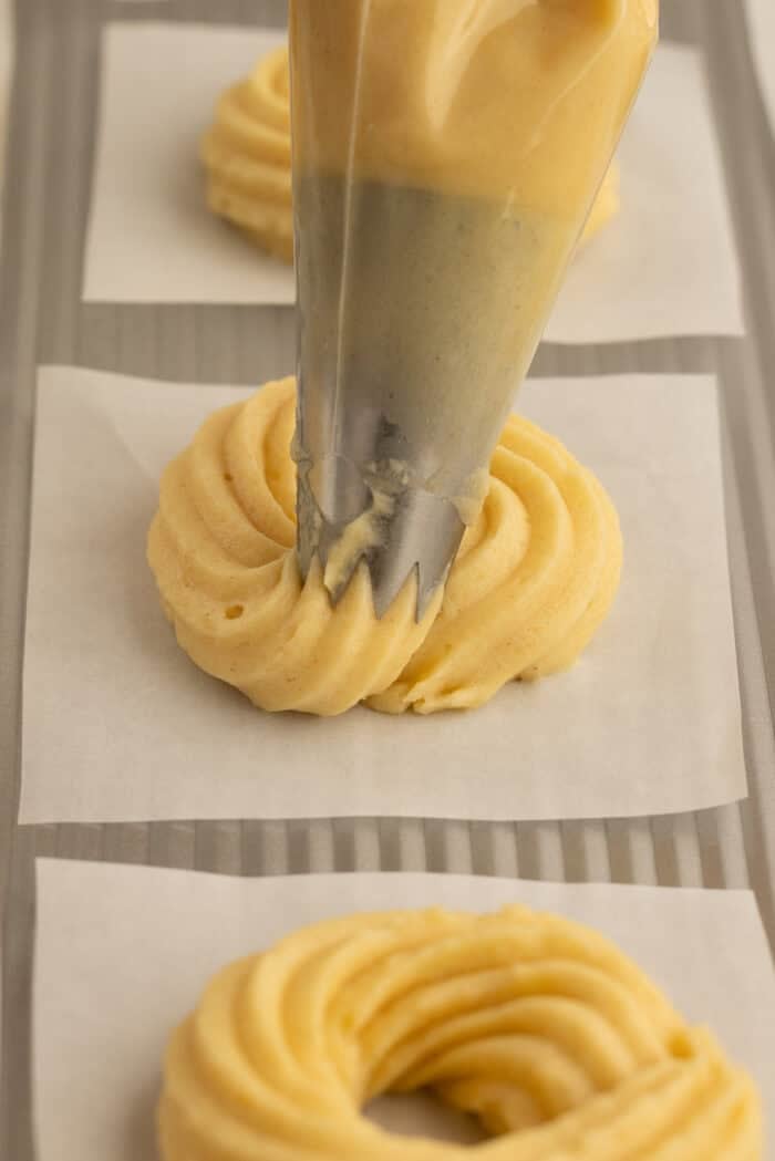 Piping choux pastry dough onto parchment squares