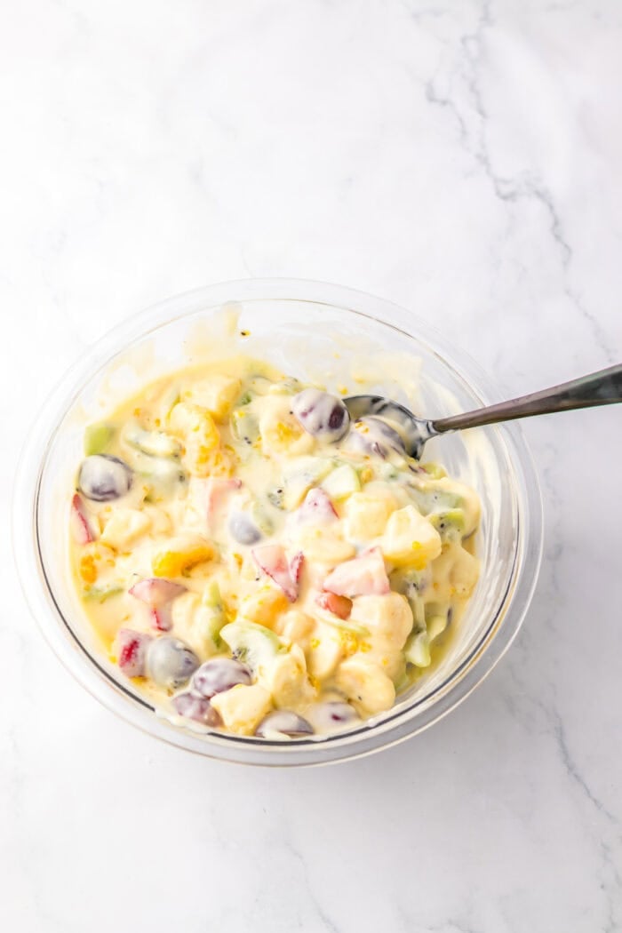 Mixing the cheesecake base into the bowl of fruit