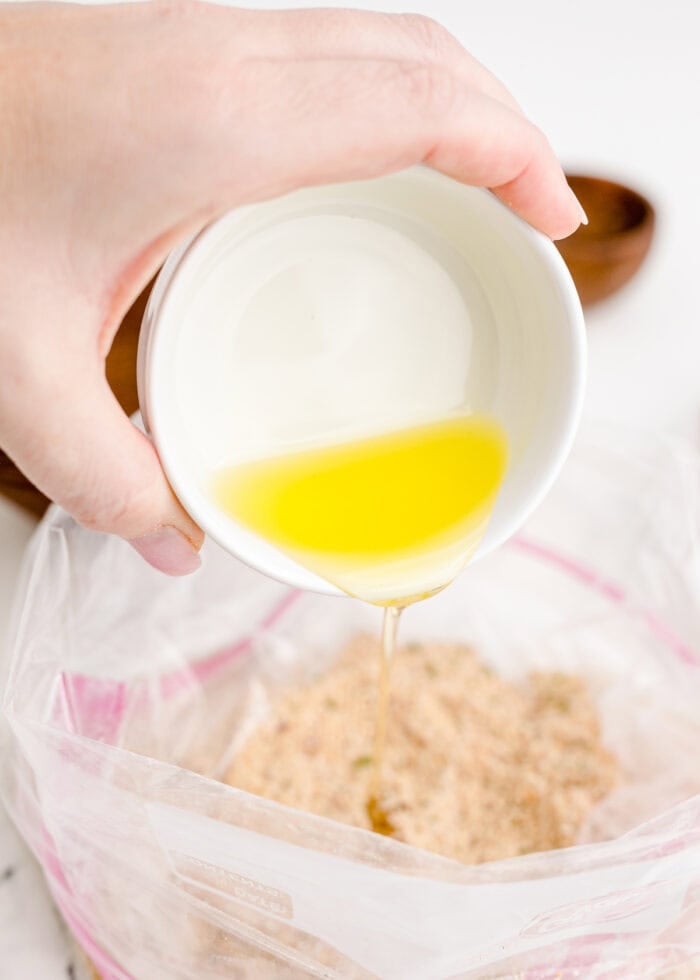 Pouring oil into a ziploc with seasoned breadcrumbs