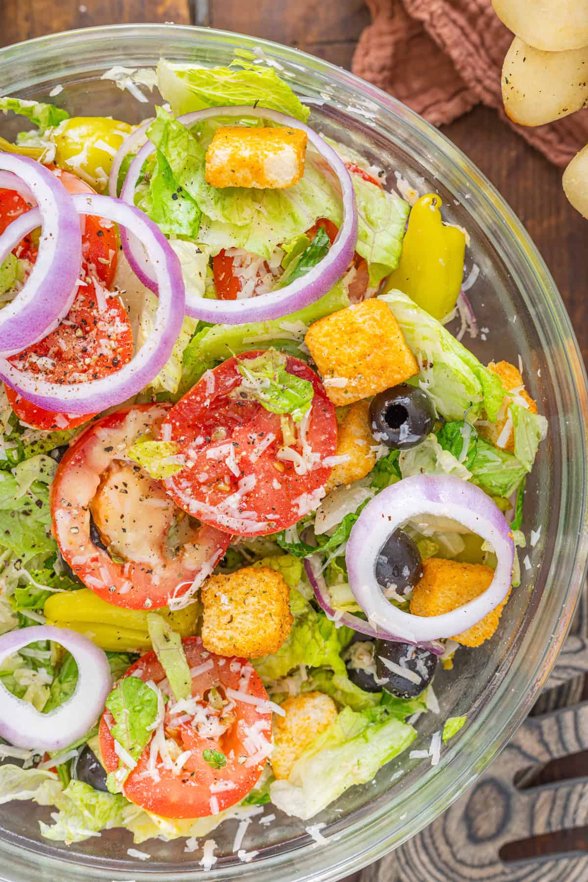 This Olive Garden Salad recipe features romaine lettuce hearts, pepperoncini, olives, and more tossed in a creamy Italian dressing. Overhead view of an Olive Garden salad