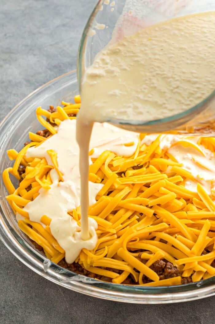 Pouring Bisquick over cheddar cheese and ground beef