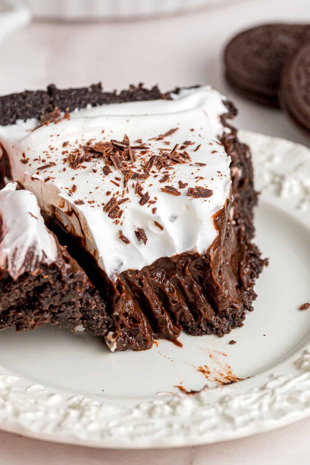 With a smooth, creamy filling in an Oreo crust, this Chocolate Pudding Pie is made in 15 minutes with 5 ingredients & 0 cooking or baking. A slice of chocolate pudding pie on a white plate with a bite on a fork