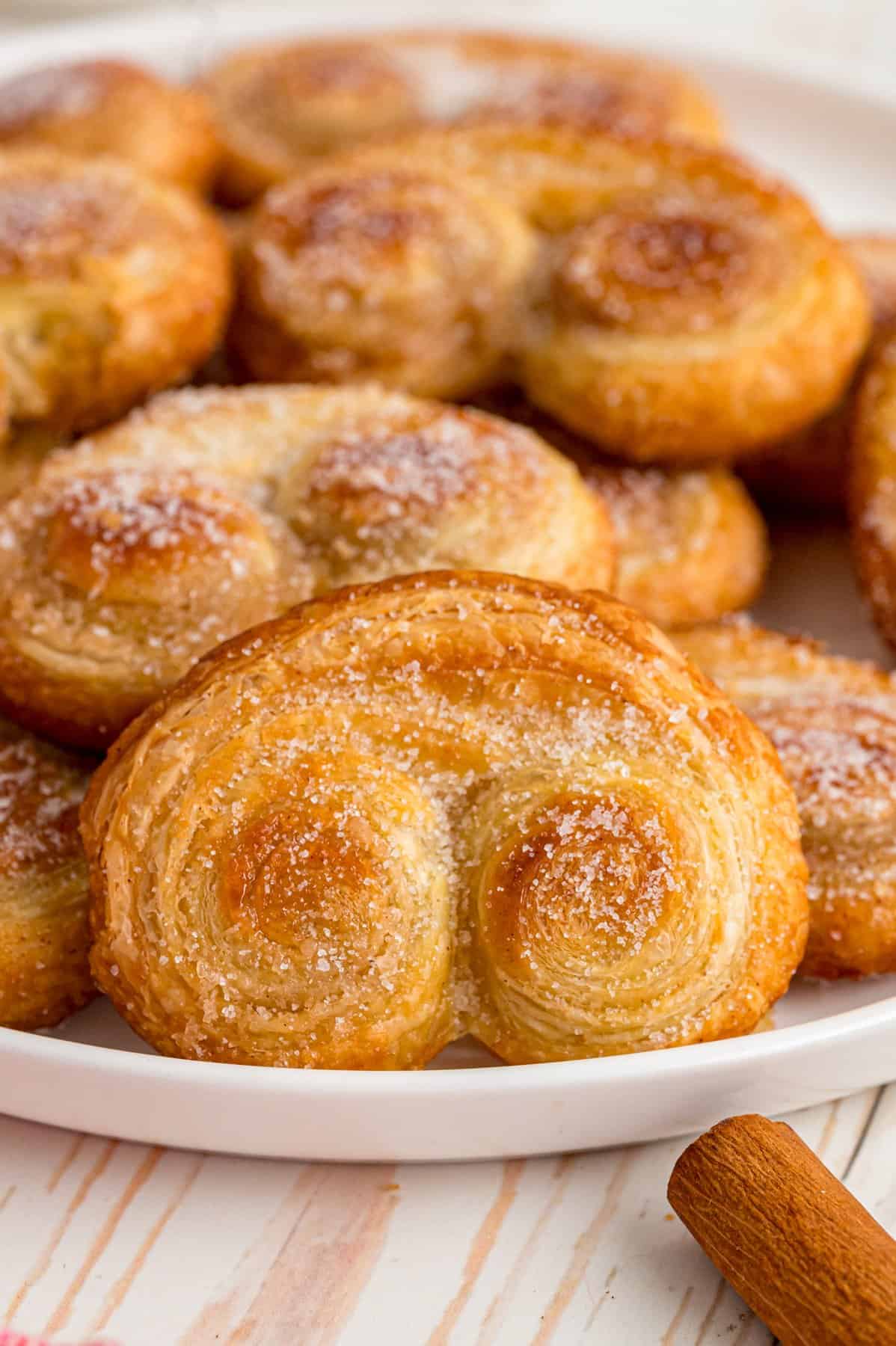 Palmiers (aka elephant ears) are an easy pastry made with puff pastry rolled with cinnamon sugar. Only 4 ingredients! A plate of palmiers