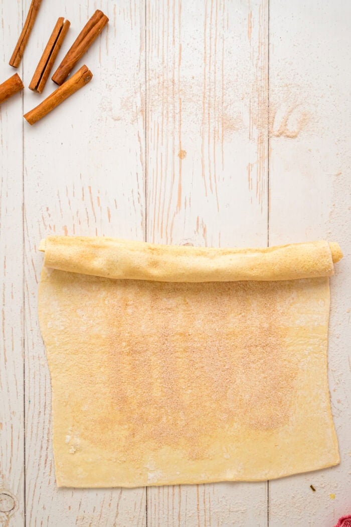 Rolling a pastry with cinnamon sugar
