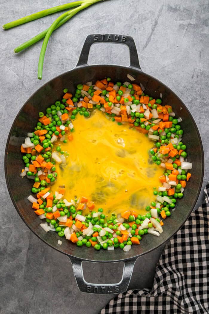 With juicy shrimp, veggies, and scrambled egg, this Shrimp Fried Rice recipe is better than takeout! Ready in just 30 minutes! Scrambled eggs surrounded by onion, peas, and carrots in a wok