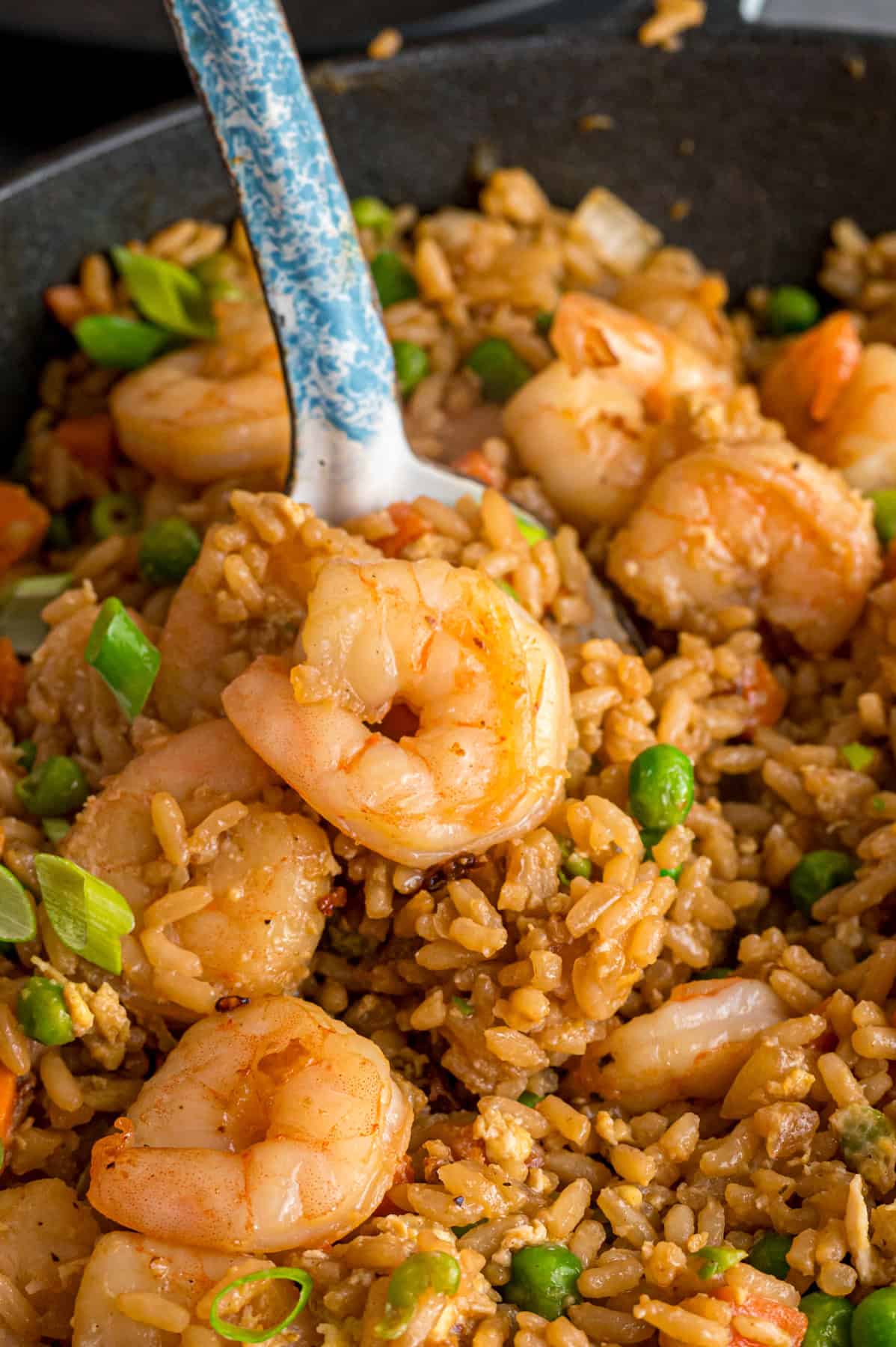 With juicy shrimp, veggies, and scrambled egg, this Shrimp Fried Rice recipe is better than takeout! Ready in just 30 minutes! Close up of a spoon of shrimp fried rice