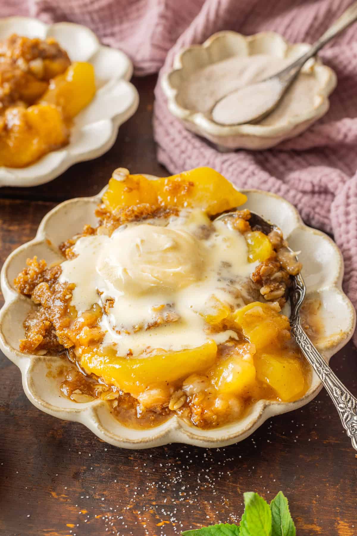 Warmly spiced fresh peaches are topped with a crumble topping in this Peach Crisp recipe. Serve with ice cream for a quick & easy dessert! A plate of peach crisp topped with vanilla ice cream